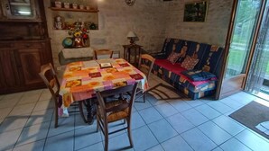 Uma sala de jantar acolhedora com uma mesa coberta por um tecido de retalhos, cadeiras de madeira e teto rústico.