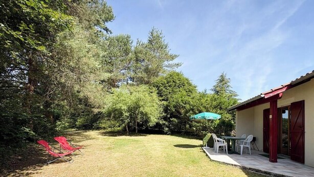 Een terras met een tafel en stoelen, een rode parasol, en een gebouw met een rood dak.