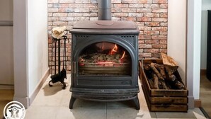 Una chimenea moderna con un fondo de pared de ladrillo, una repisa y un cuadro enmarcado encima.