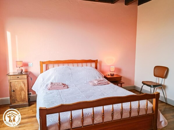 Un dormitorio con una cama de madera, dos mesitas de noche con lámparas, una silla y un armario.