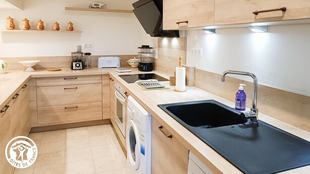 Una cocina moderna con armarios de madera, lavavajillas integrado, un fregadero y una cafetera.