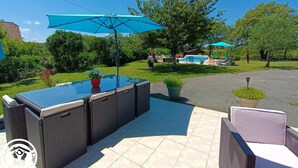 A patio area with a hot tub, outdoor furniture, and a pool in the background.
