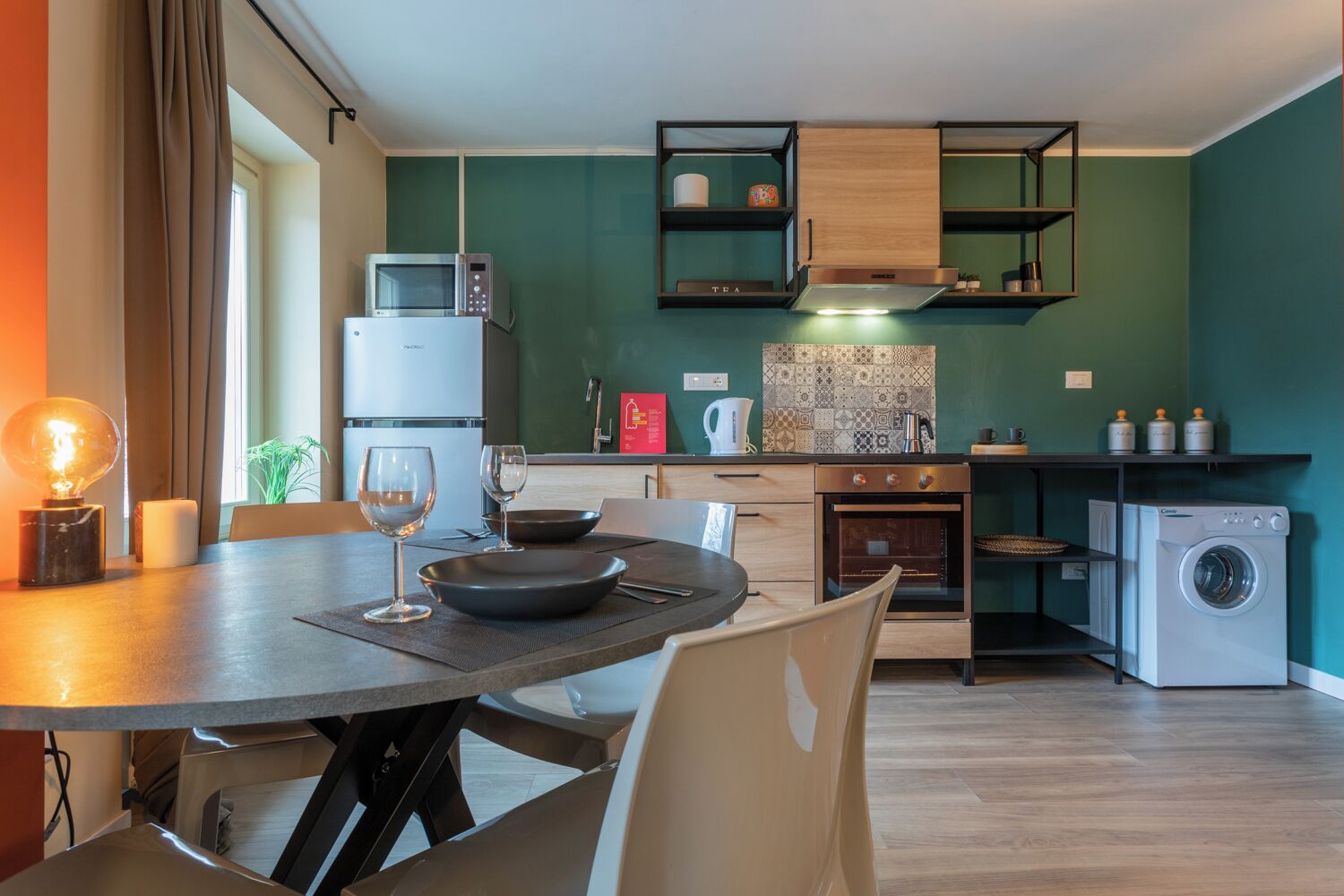 A compact kitchen with modern appliances, a dining area with a table and chairs, and a washing machine.
