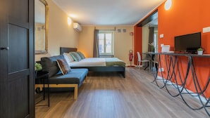 Una habitación moderna con cama, sofá y escritorio con computadora.