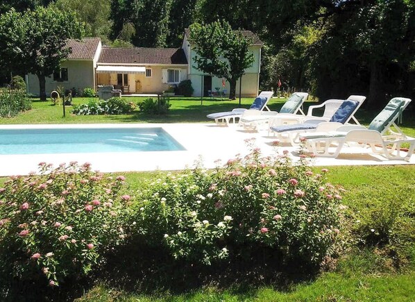A swimming pool with lounge chairs, surrounded by a well-maintained garden and a house in the background. - Chez Lola - Vayrac - Gîte (VAYRAC)