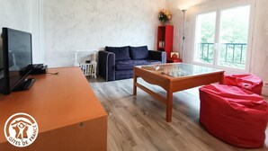 Ein Zimmer mit einem Holztisch, einer Couch, einem Glastisch und einem roten Sitzsack.