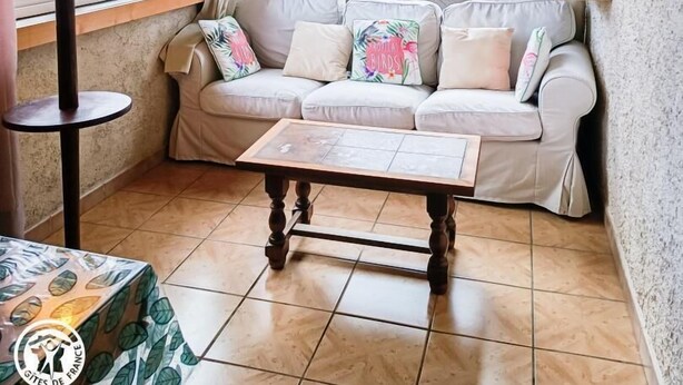 Una sala de estar acogedora con un sofá, una mesa, una lámpara y vistas amplias por las ventanas.