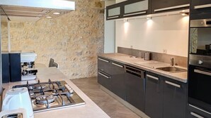 A modern kitchen with a gas stove, a coffee machine, and a dishwasher. - Gîtes de France® - 46G12322 (SAUZET)
