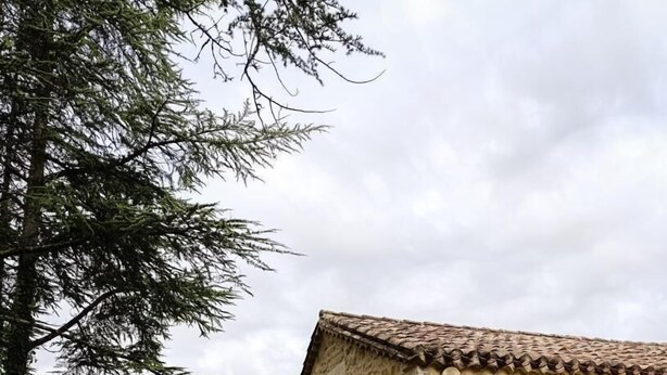 A rustic stone building with a tiled roof and a small window with blue shutters. - Gîtes de France® - 46G12322 (SAUZET)
