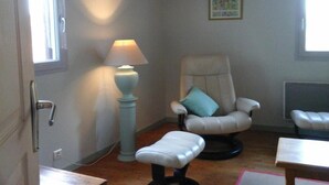 A room with a chair, a small table, a lamp, and a window. - Gîtes de France® - LA TOUR (CREYSSE)