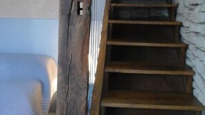 A wooden staircase with a dog resting on the top step. - Gîtes de France® - LA TOUR (CREYSSE)
