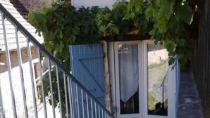 A dog standing at the base of a staircase with a blue door and a metal railing. - Gîtes de France® - LA TOUR (CREYSSE)