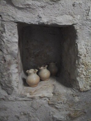 Un muro de piedra con un pequeño nicho que contiene tres objetos de cerámica.