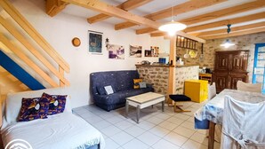 Ein gemütliches Wohnzimmer mit einer Couch, einem kleinen Tisch und einem Bett. Es gibt eine Küchenzeile mit Schränken und einer Spüle.