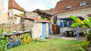 Ein rustikaler Innenhof mit Steinhäusern, einem Holztisch und einem Fahrrad.