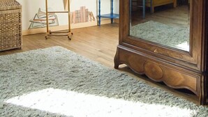 Ein Schlafzimmer im Loft-Stil mit schrägverdeckter Decke, Dachfenstern, einem großen Holzerspiegel, einem Holzschrank und einem kleinen Tisch mit Stuhl.