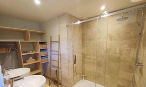 Ein Badezimmer mit Dusche, zwei Waschbecken und Holzregalen.