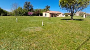 A house with a red-tiled roof, a large lawn, and a tree. - Gîtes de France® - Le TRUFFADOU (SAUZET)