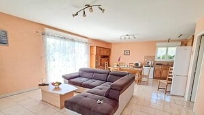 A compact living space with a sofa, a small dining table, and a kitchen area. - Gîtes de France® - Le TRUFFADOU (SAUZET)