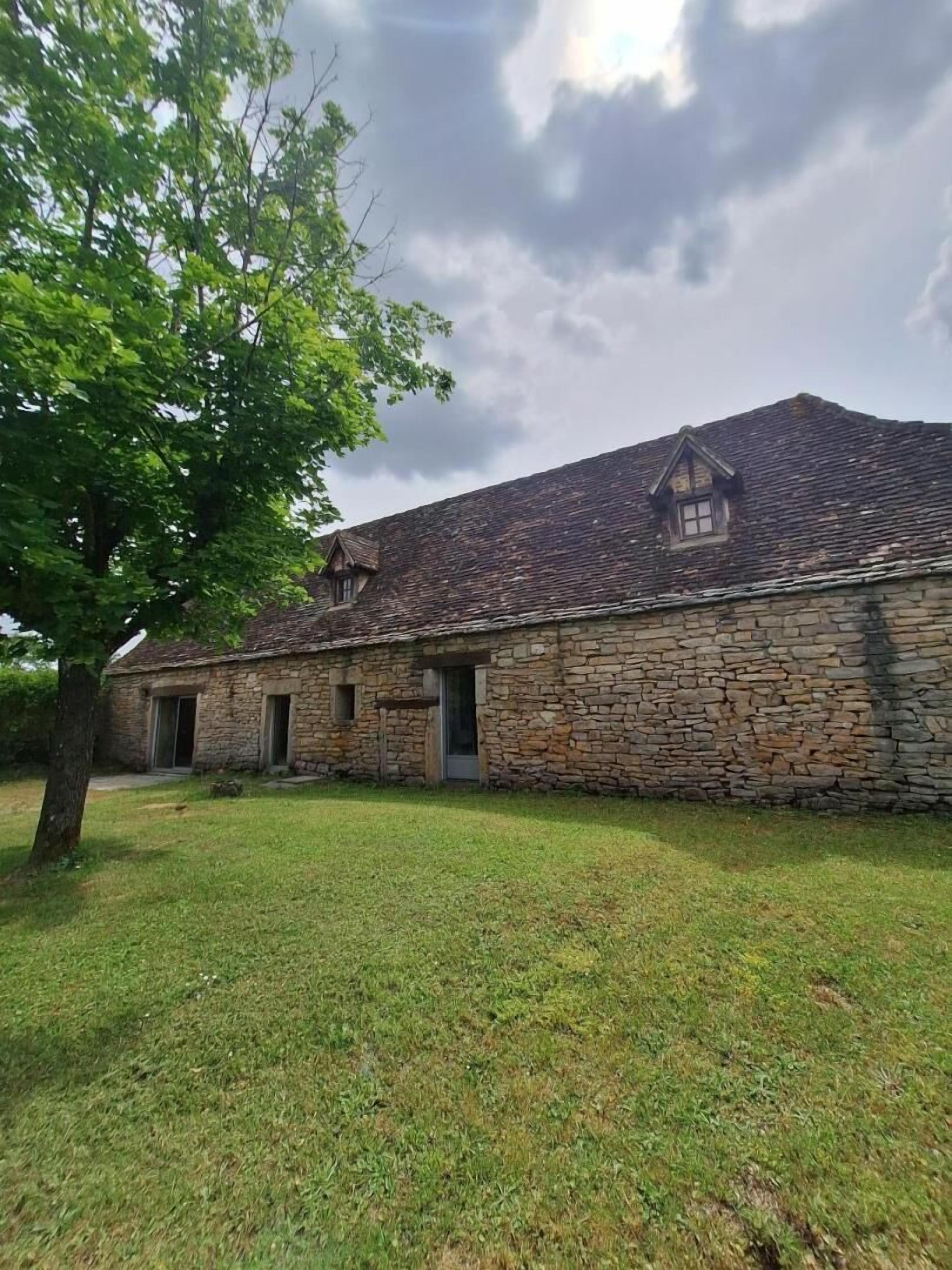 A stone building with a sloped roof, a small window, and a door.