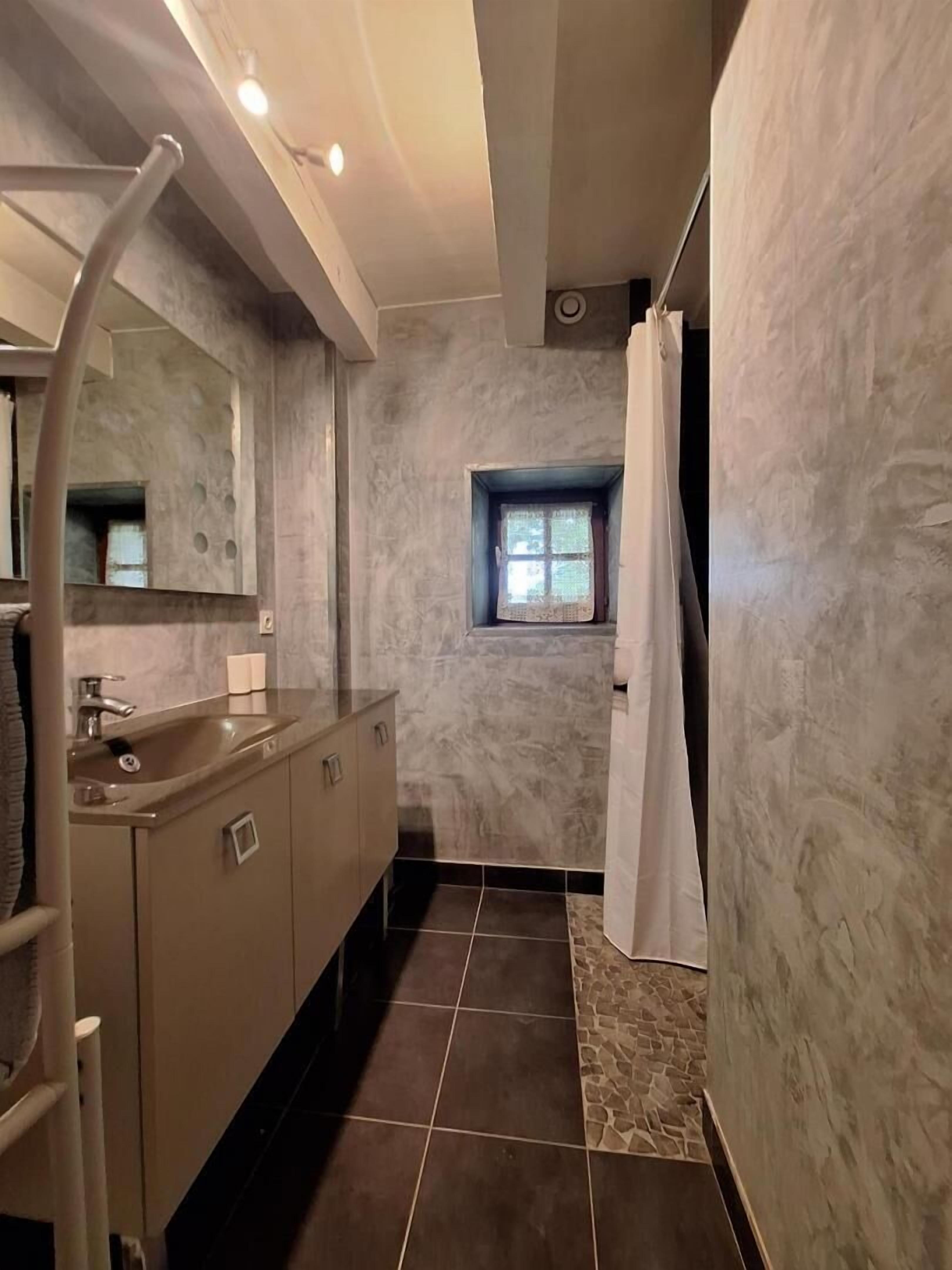 A bathroom with a sink, mirror, and window.