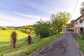 A rural road with a white building on the right, surrounded by greenery and fields. - Gîtes de France® - The Green View   (SAINT PERDOUX)
