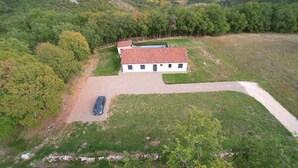 A two-story house with a red-tiled roof, surrounded by a grassy yard and trees. - Gîtes de France® - La Bouysse (SERIGNAC)