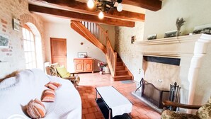 Un salon chaleureux avec une cheminée, un escalier et un lit agrémenté d’oreillers.