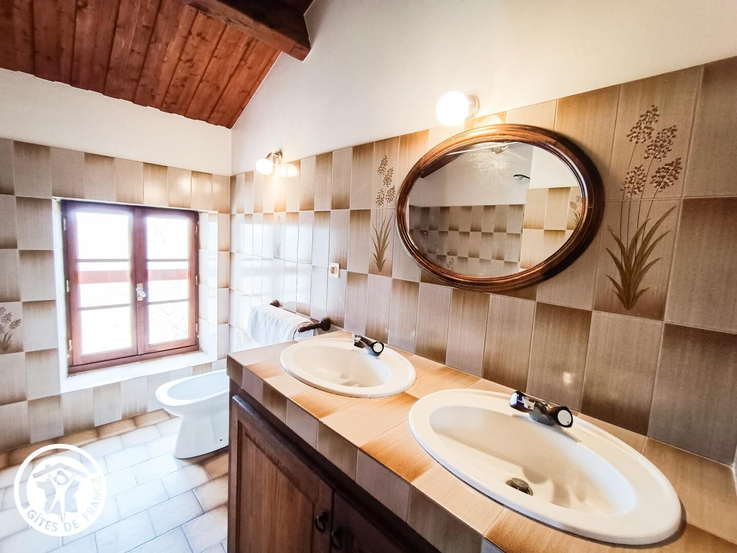 Un baño con dos lavamanos, un espejo y una ventana.