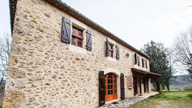 Un bâtiment en pierre doté d’un porche couvert, d’une porte en bois et d’une fenêtre avec des volets.
