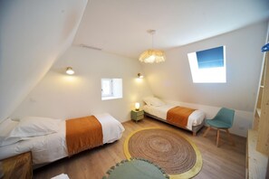 Ein kleines, gemütliches Schlafzimmer mit zwei Betten, einem Fenster, einem Sessel und einem Teppich.