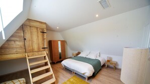 A bedroom with a loft bed, a wooden wardrobe, a bedside table, a lamp, and a yellow rug. - Gîtes de France® - Gîte des Escures (SAINT CHELS)