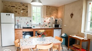 Cocina compacta con refrigerador, microondas y estufa. Hay una mesa de comedor con sillas y una ventana que proporciona luz natural.