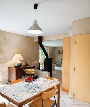 Ein Essbereich mit einem Tisch für zwei Personen, einer Lampe und Blick in die Küche.