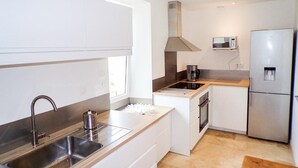 A modern kitchen with stainless steel appliances, a built-in oven, and a microwave. - Gîtes de France® - La Belle Lotoise (TEYSSIEU)