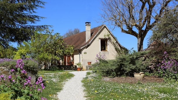A house with a gravel path leading to the entrance, surrounded by lush greenery and flowering plants. - Gîtes de France® - Gîte les Gratabels (BASTIT (LE))