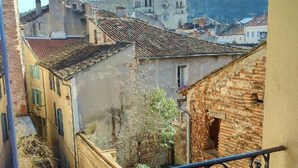 A balcony with wrought iron railings overlooking a town with historic buildings and a church.