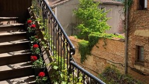 A staircase with a metal railing, potted plants, and a hanging flower pot.