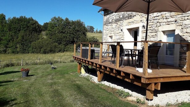 Ein Steinhaus mit einer Holzterrasse und einem Sitzbereich im Freien.
