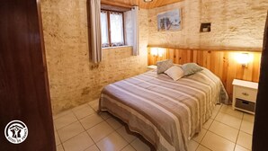 Ein Schlafzimmer mit Holzboden, einem Bett mit gestreifter Bettwäsche, einem Nachttisch und einer Wandlampe.