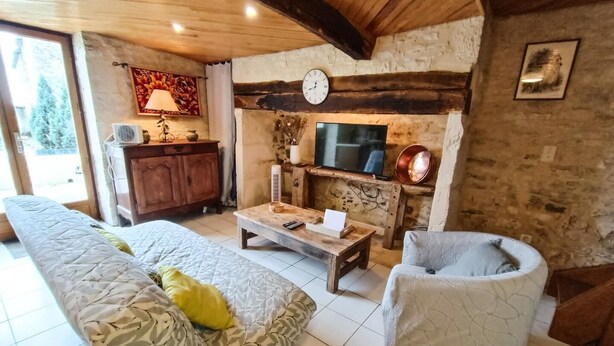 Ein gemütliches Wohnzimmer mit einer Couch, einem Couchtisch, einem Fernseher und einer Steinwand.