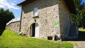 A stone building with a single entrance, a small porch, and a staircase leading up to the entrance. - Gîtes de France® - Gîte du Fau (BESSONIES)