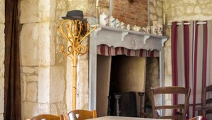 A rustic interior with stone walls, a wooden coat rack, a fireplace, and striped curtains.