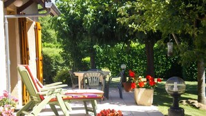 Un patio con mobiliario exterior, una mesa y plantas en macetas.