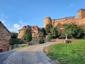 A castle with a cobblestone path leading to a stone building with a red roof.