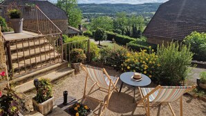 Un patio con vista sulla valle, una scala in legno e un tavolino con un cappello.