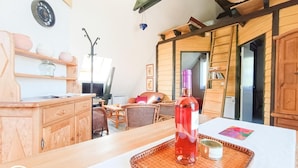 A cozy room with wooden furniture, a bottle on a tray, and a wicker basket on the ceiling.