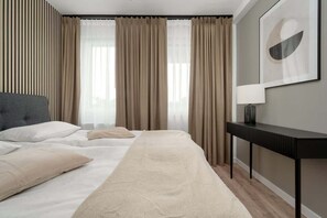 Une chambre d’hôtel moderne avec un grand lit, une table de chevet et une fenêtre avec des rideaux.