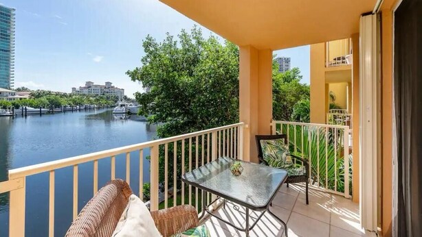 A balcony with a table and chairs, overlooking a river with boats and buildings in the background. - Best view in Aventura Yacht Club, 2-bedroom condo fully equipped  (Aventura)