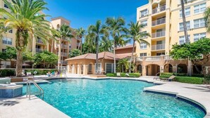 A swimming pool surrounded by palm trees and a multi-story building with balconies. - Best view in Aventura Yacht Club, 2-bedroom condo fully equipped  (Aventura)